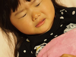 苦しそうに目を閉じる幼児