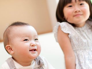 お姉ちゃんの傍で笑う赤ちゃん