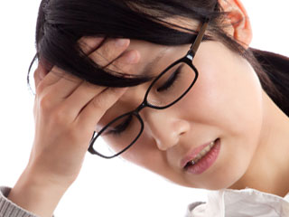 額に手を当てて俯く女性