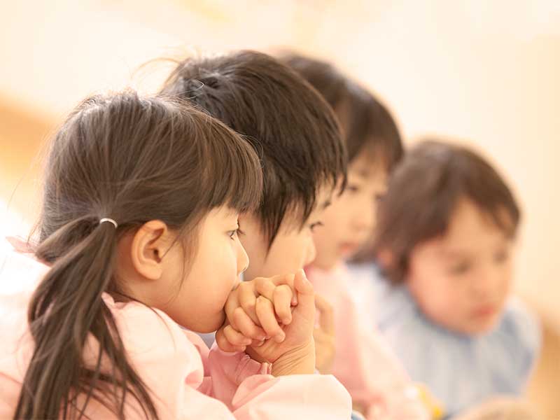 4人固まって話を聞いている保育園児達