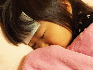 額に熱さましシートを貼って寝る子供