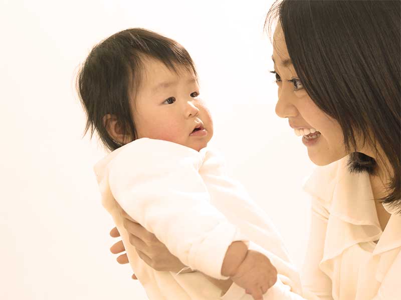 赤ちゃんの生えかけている歯を見ている母親