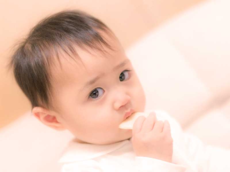 お菓子を口に入れている赤ちゃん