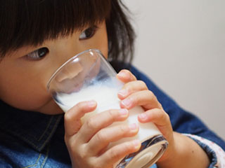 コップで牛乳を飲む幼児