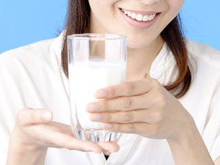 牛乳の入ったコップを差し出す女性