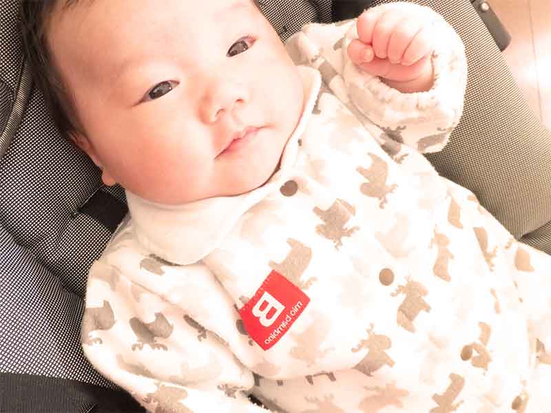 ベビーベッドに寝かされ笑顔の新生児