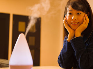 加湿器から出る蒸気を見る女性