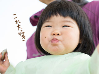 手づかみにした離乳食をおいしそうに食べる赤ちゃん