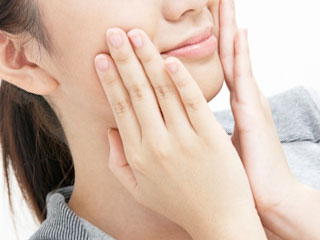 頬を両手で触る女性