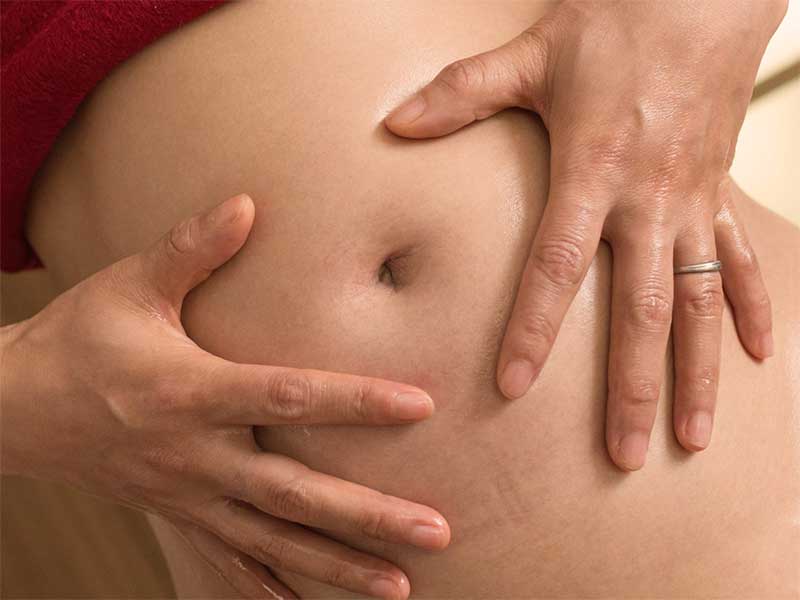 お腹に保湿クリームを塗っている妊婦