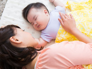 赤ちゃんを見守りながら添い寝する女性
