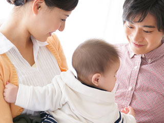 母親に抱っこされる赤ちゃんを父親が見守る