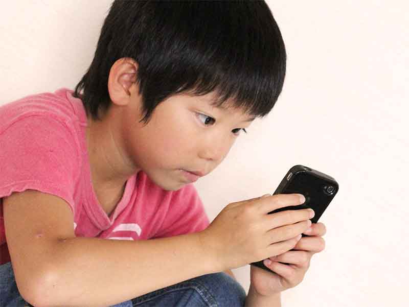 猫背でスマホを使っている男の子