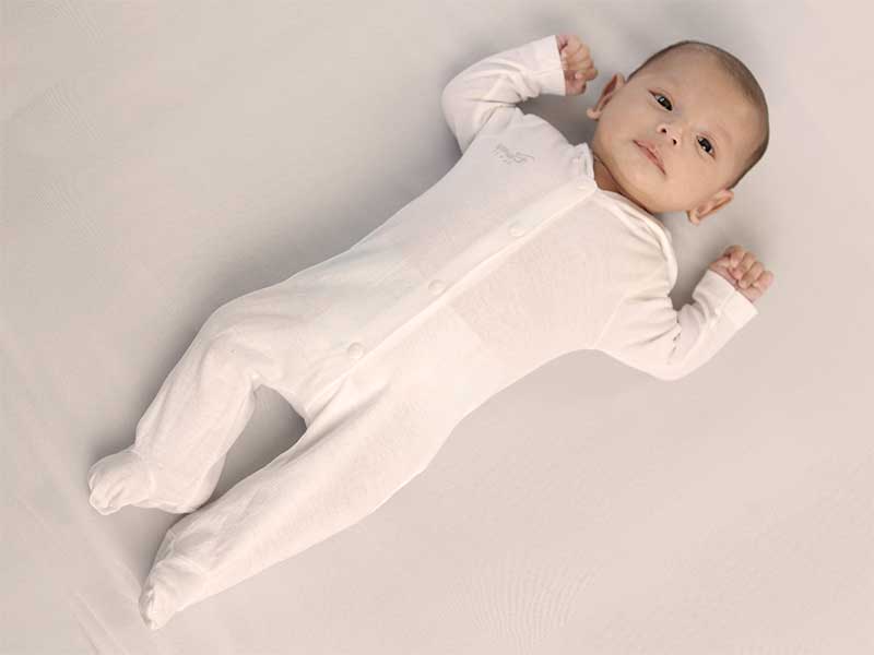 足を伸ばした状態で仰向けで寝ている新生児