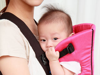 抱っこひもでお母さんと向かい合って抱かれる赤ちゃん