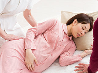 看護師に横向きにされる妊婦