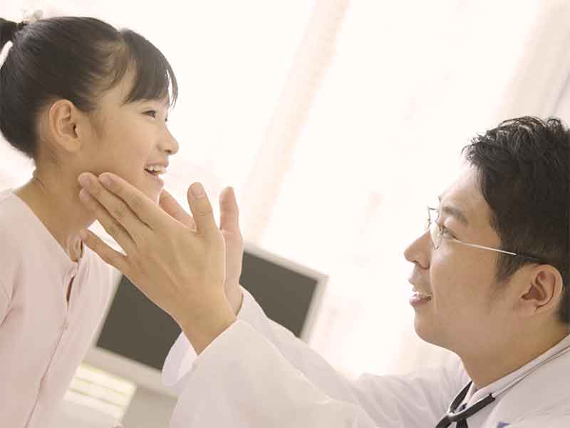病院で医者に首を診察してもらっている女の子