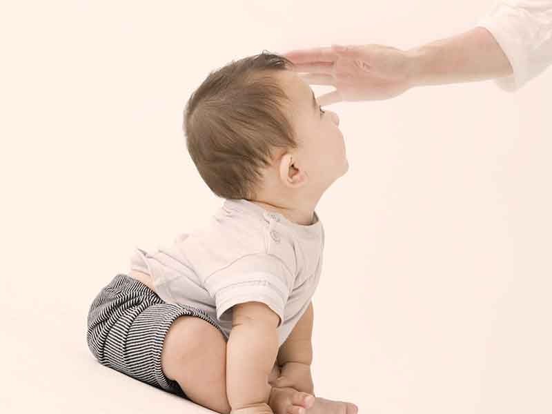 赤ちゃんの頭を撫でている母親の手