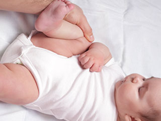 赤ちゃんの片足を持って、お腹に膝を押し付ける運動をする