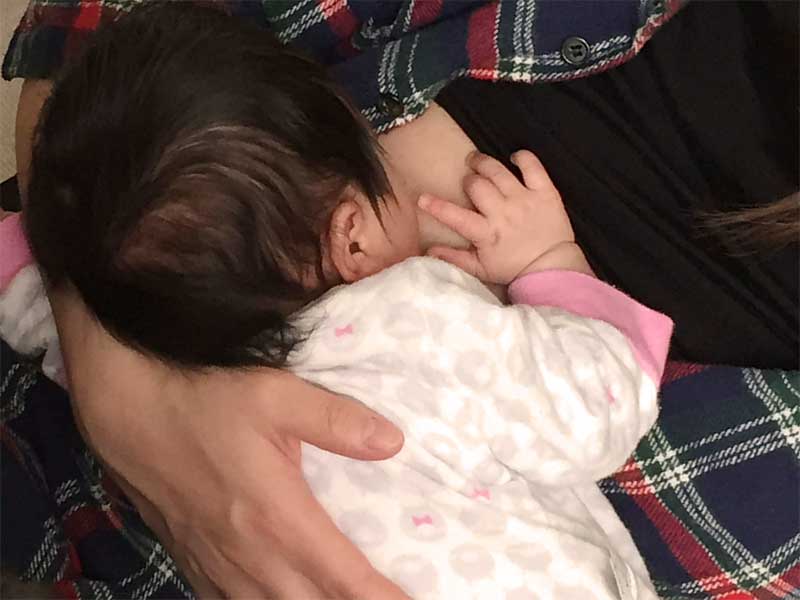 無理な体勢で授乳されている新生児