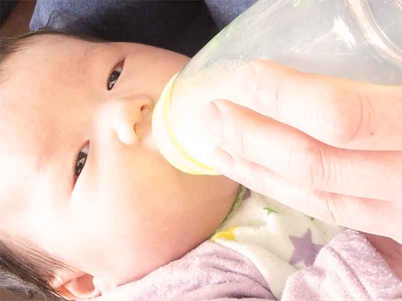 哺乳瓶でミルクを飲んでいる新生児