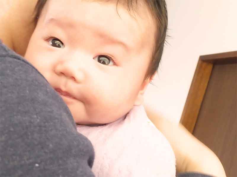 抱っこで背中をトントンされてもゲップがなかなか出ない新生児の顔