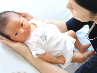 赤ちゃんを両手で暖めるお母さん