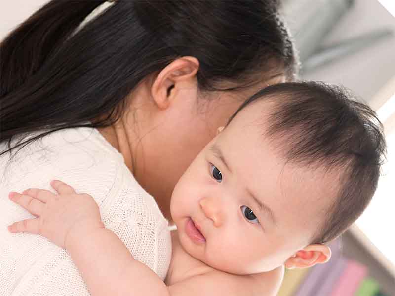 笑顔の新生児を抱っこしてる母親