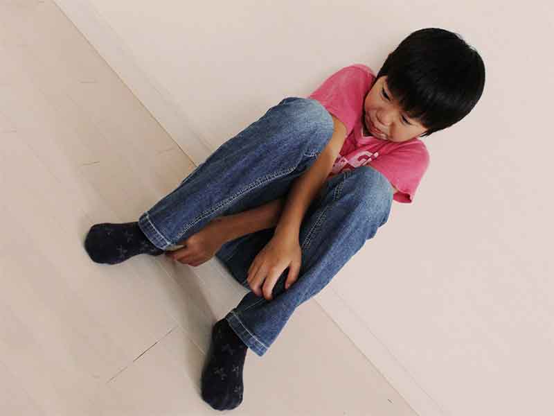 壁に寄りかかりながら座って泣いている男の子