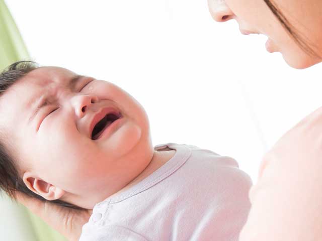 泣く赤ちゃんをあやす母親