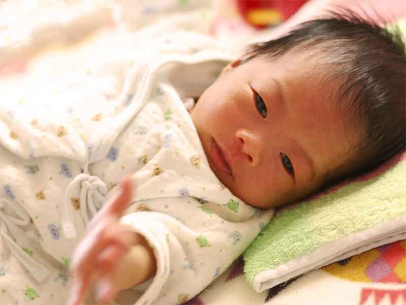 寝ながら手を振っている新生児