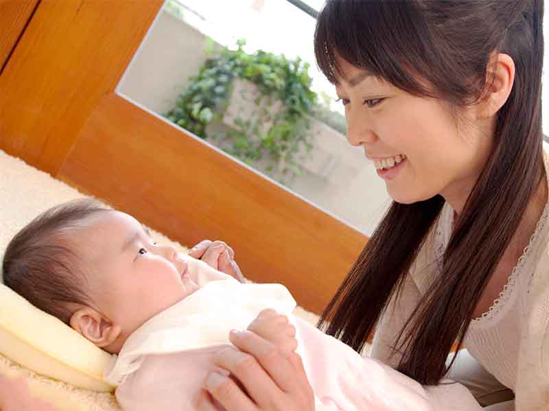 新生児に顔を近づけて歌っている母親