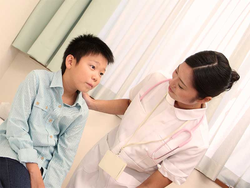 病院で看護師と一緒にいる男の子