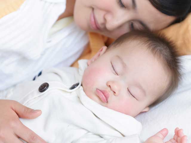 赤ちゃんに添い寝する母