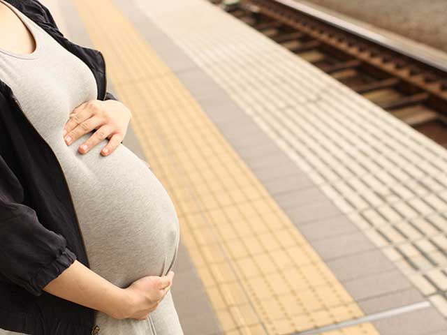 駅のホームで電車を待つ妊婦