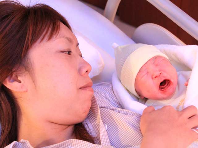 新生児と一緒にベッドに寝る女性
