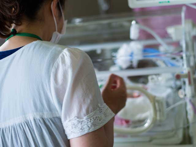 新生児室で赤ちゃんを見る女性