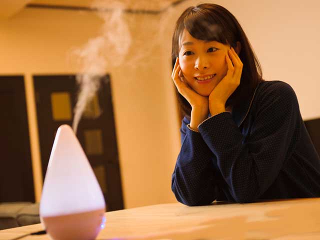 加湿器の前で水蒸気を見つめる女性