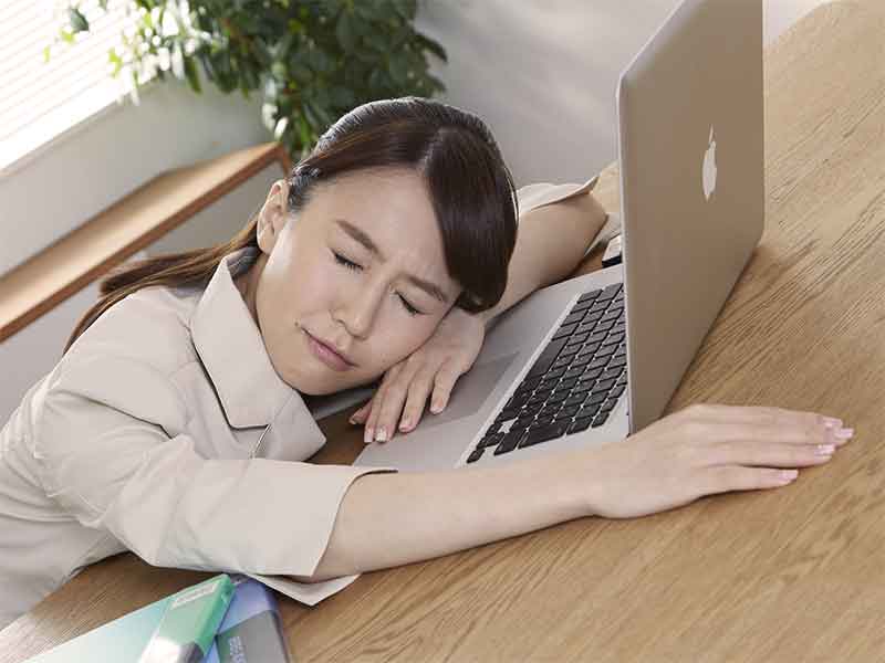 仕事が忙しくて会社のパソコンの前で突っ伏している女性