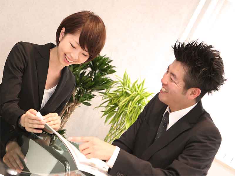 会社で同じ資料を触っている男女