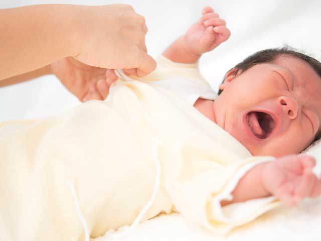 泣く赤ちゃんの着替えをする母親