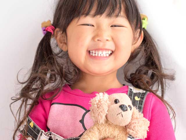 ぬいぐるみを持って笑顔の幼児