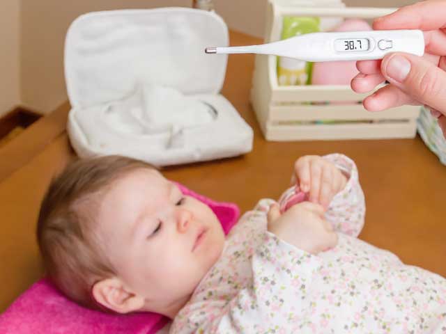 赤ちゃんと体温計を持つ親の手