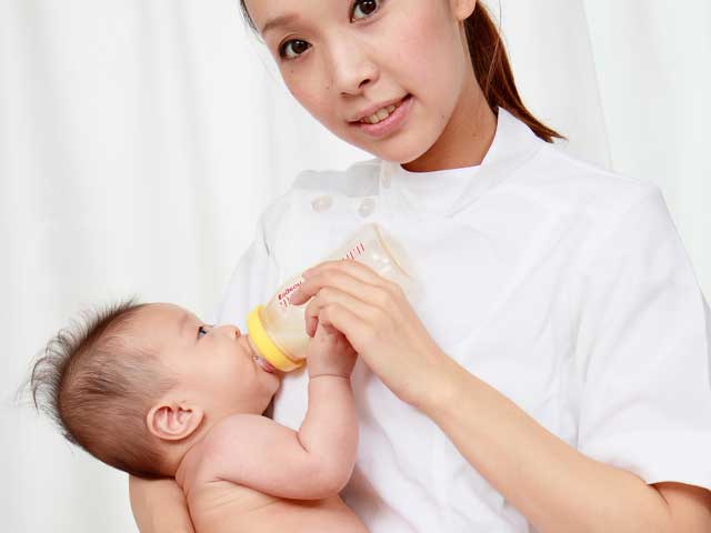 看護師にミルクを飲ませてもらう赤ちゃん