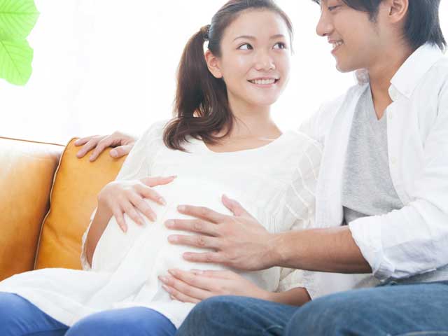 妊婦の妻のお腹に手を当てる夫