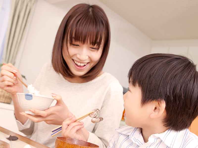 ご飯を食べて笑顔の男の子と母親