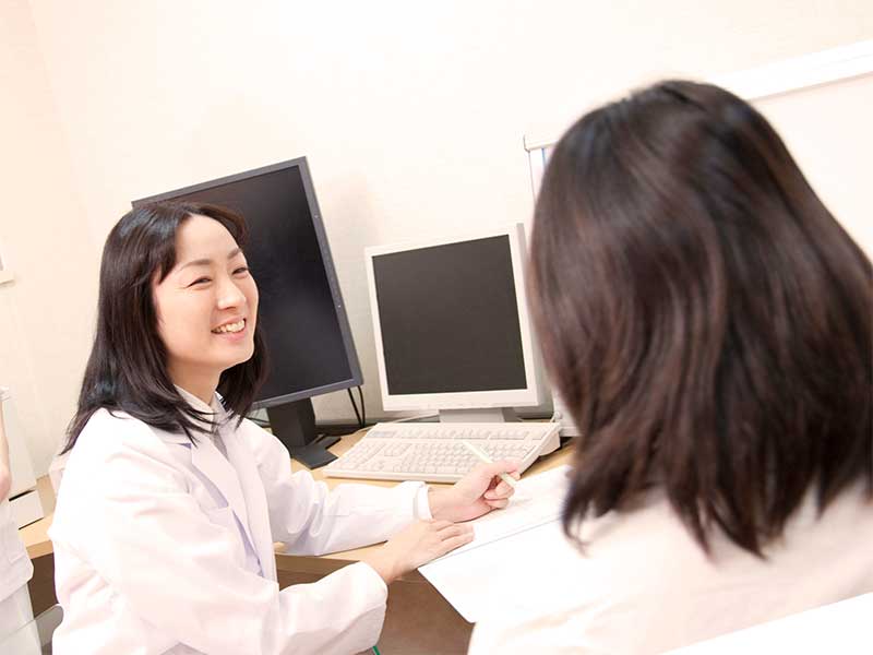 産婦人科で医師に相談する妊娠している女性