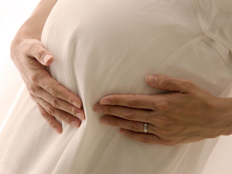妊娠してふくらんだお腹を押さえている母親
