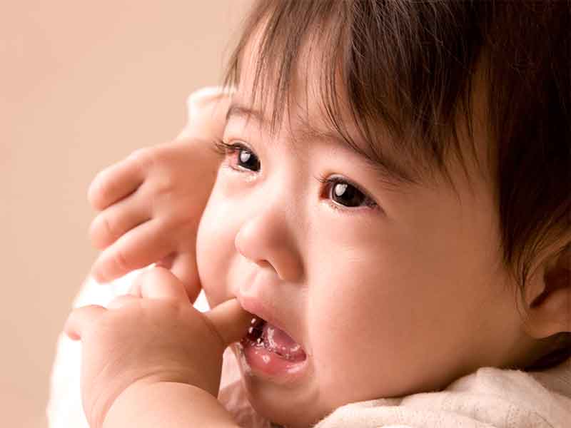 泣きながら口内炎を指で触ってる赤ちゃん