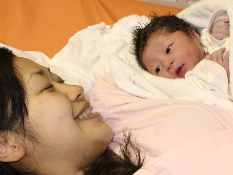 生まれたばかりの赤ちゃんを見つめるお母さん